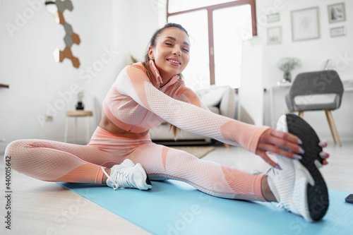 Young fit woman doing stretching exercises at home