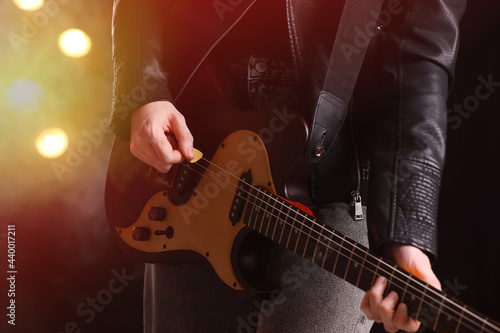 Man playing electric guitar on stage, closeup. Rock concert