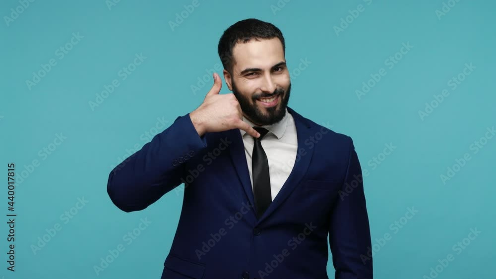 Contact us. Positive young bearded brunette man in black suit holding fingers near ear showing call gesture, feel free to call, call center. Indoor studio shot isolated on blue background. Contact us. Positive young bearded brunette man in black suit holding fingers near ear showing call gesture, feel free to call, call center. Indoor studio shot isolated on blue background.