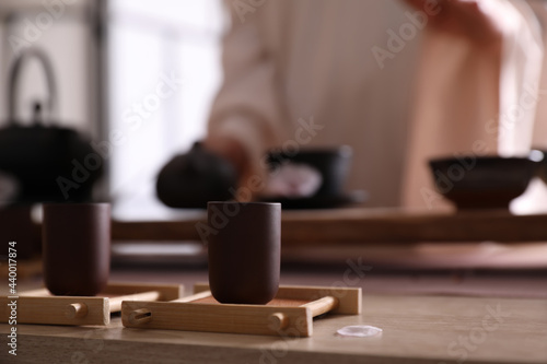 Master conducting traditional tea ceremony at table indoors, focus on cup