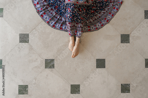Woman wearing blue and red dress on tile floor viewed from above