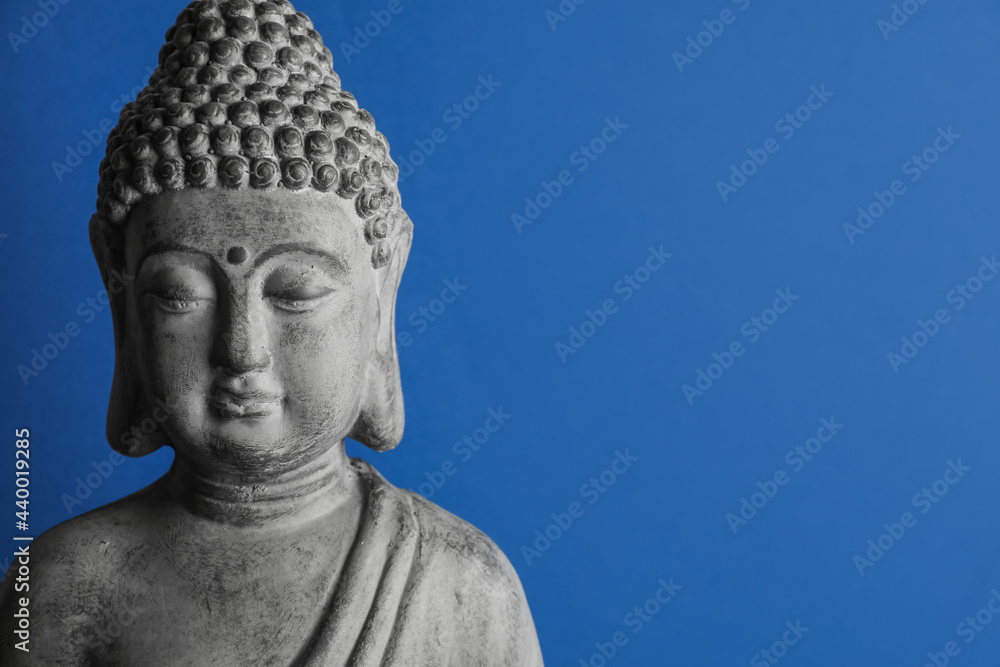 Beautiful stone Buddha sculpture on blue background. Space for text