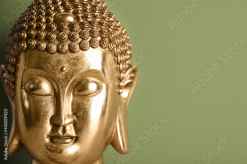 Beautiful golden Buddha sculpture on green background, closeup. Space for text