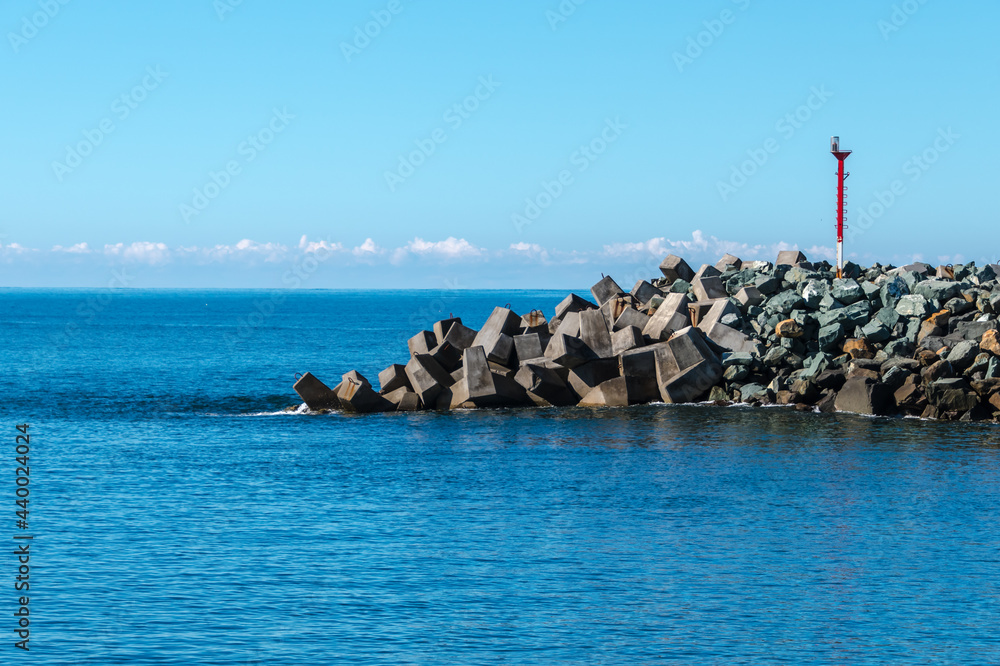 The blue river leading into the sea and rocky breakwall