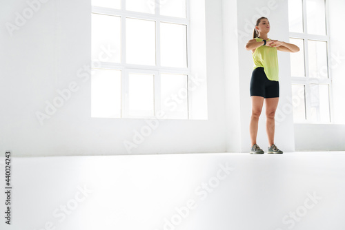 Young white sportswoman doing exercise while working out indoors