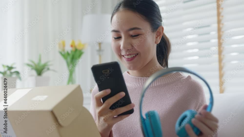 Young asia people happy teen girl smile unbox open gift new headphone buy order from online store shop take photo shoot camera show post social media app blog vlog share sit relax at home sofa couch. Young asia people happy teen girl smile unbox open gift new headphone buy order from online store shop take photo shoot camera show post social media app blog vlog share sit relax at home sofa couch.
