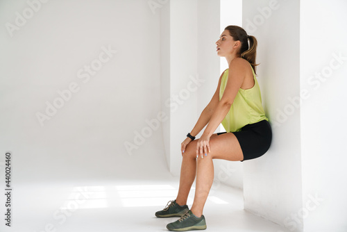 Young white sportswoman doing exercise by wall while working out