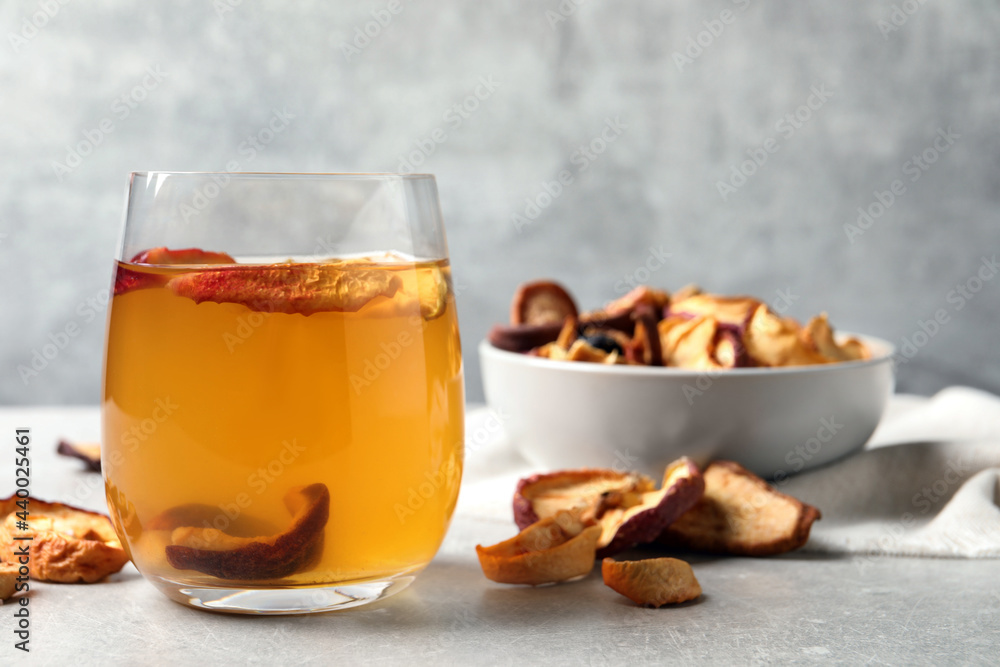 Delicious compote with dried apple slices in glass on grey table, space for text Delicious compote with dried apple slices in glass on grey table, space for text