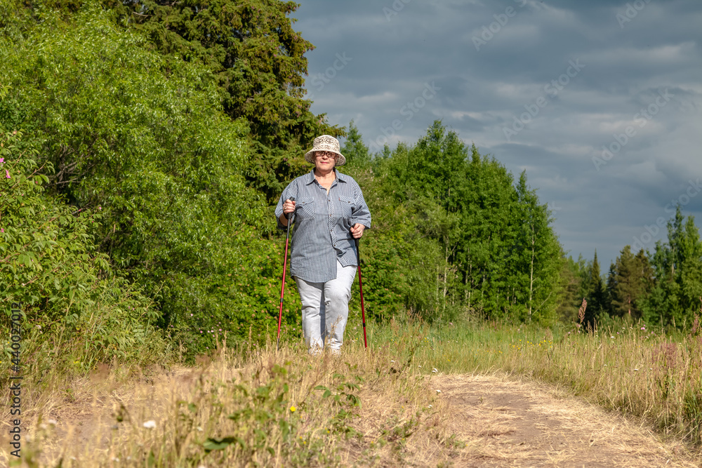 The grandmother is engaged in Scandinavian walking. An elderly woman goes in for sports.