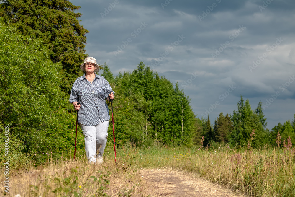 The grandmother is engaged in Scandinavian walking. An elderly woman goes in for sports.