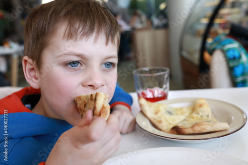 Child eating piece of four cheese pizza