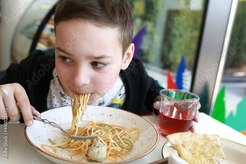 Kid eating spaghetti with chicken meatballs