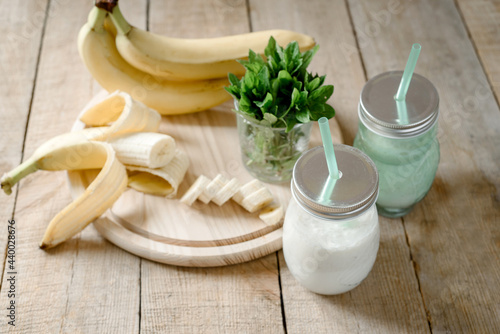 Summer banana smoothie or milkshake with mint and straw in jars on dark wooden tablen with copy space photo