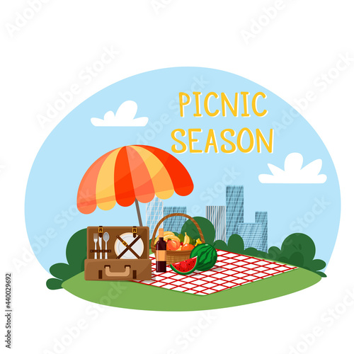 Vector illustration of a park in the city. City landscape in the background. Umbrella, blanket, picnic basket with fruit and baguette, picnic suitcase with utensils. Cartoon style.