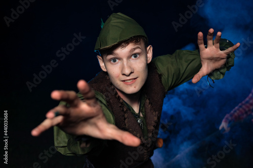 Cosplay on Peter Pan. A young man in a Peter Pan costume stands amid blue smoke at night