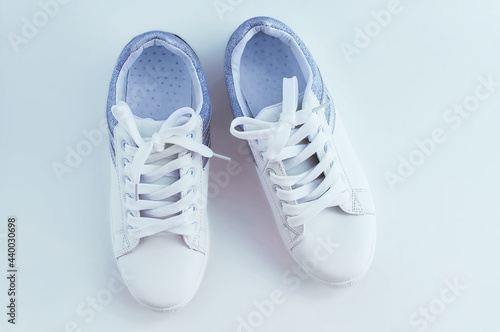 White sneakers with laces with silver inserts on white background. View from above.