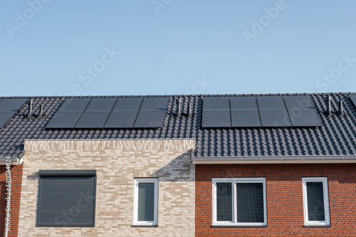 Newly build houses with solar panels attached on the roof against a sunny sky Close up of new building with black solar panels. Zonnepanelen, Zonne energie, Translation: Solar panel, , Sun Energy photo