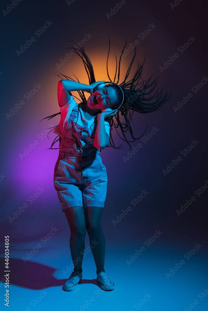 Caucasian young woman's portrait on dark studio background in neon. Concept of human emotions, facial expression. Caucasian young woman's portrait on dark studio background in neon. Concept of human emotions, facial expression.