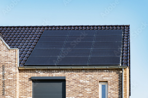 Newly build houses with solar panels attached on the roof against a sunny sky Close up of new building with black solar panels. Zonnepanelen, Zonne energie, Translation: Solar panel, , Sun Energy photo