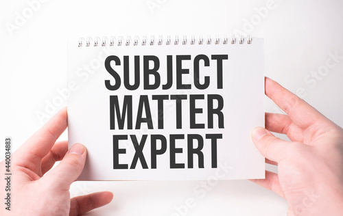 SUBJECT MATTER EXPERT word inscription on white card paper sheet in hands of a man. Black letters on white paper. Business concept.