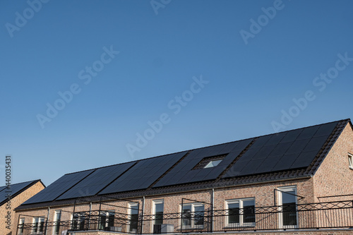 Newly build houses with solar panels attached on the roof against a sunny sky Close up of new building with black solar panels. Zonnepanelen, Zonne energie, Translation: Solar panel, , Sun Energy photo