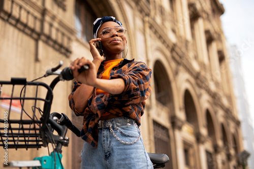 Happy young woman riding bicycle in the city. Beautiful african woman enjoying outdoors.