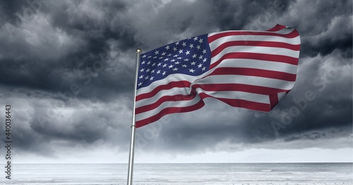 Composition of waving american flag against stormy sky and seaside