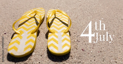 Composition of happy 4th of july text with flip flops on sand