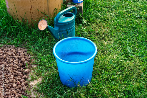 watering can and bucket stand by the barrel in the garden
