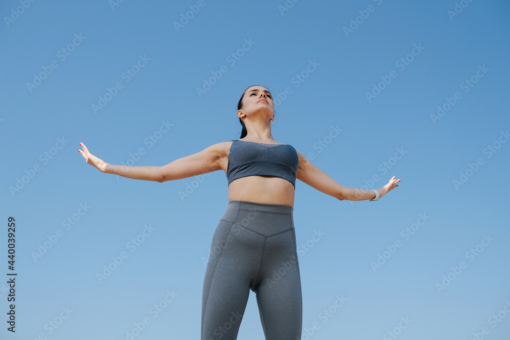 Majestic young woman in sportswear greetng the sun. Over blue sky Majestic young woman in sportswear greetng the sun. Over blue sky