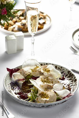 Traditional Italian cuisine Vitello tonnato with a glass of white wine, marinated veal appetizer with creamy tuna sauce on a light, festive table. photo