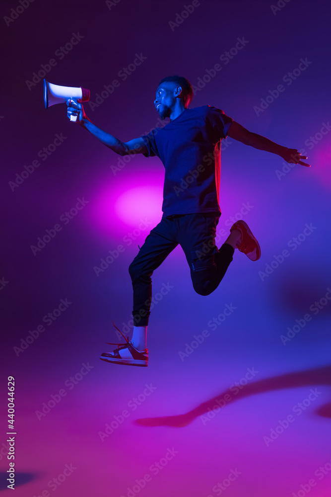African young man isolated on blue studio background in neon. Concept of human emotions, facial expression.