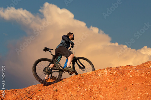 Conquering mountain peaks by cyclist in shorts and jersey on a modern carbon hardtail bike with an air suspension fork . Beautiful view from the mountain.