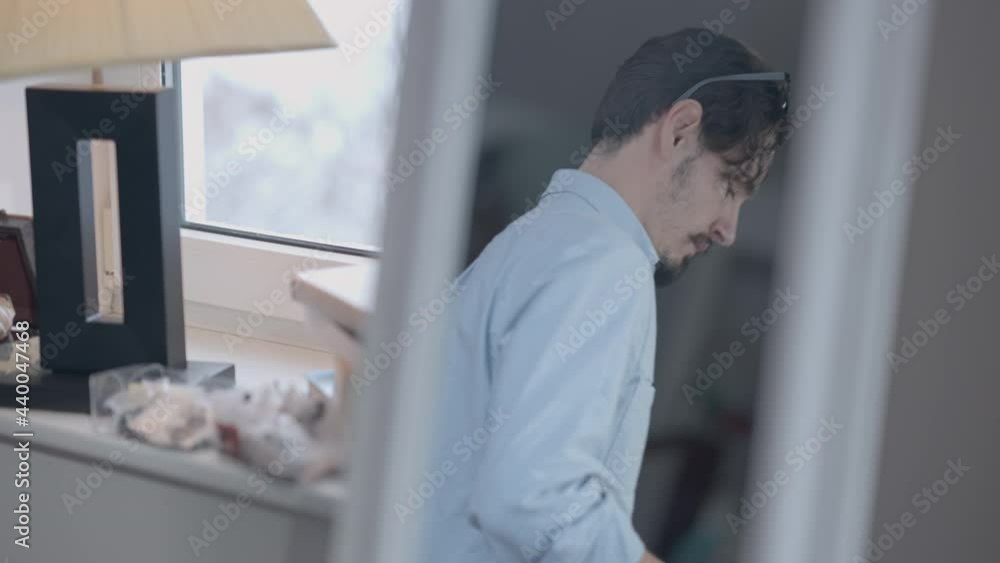 Male Caucasian fashion designer reflecting in mirror putting measuring tape on shoulders and walking away. Reflection of confident skilled handsome man thinking on new collection idea in atelier Male Caucasian fashion designer reflecting in mirror putting measuring tape on shoulders and walking away. Reflection of confident skilled handsome man thinking on new collection idea in atelier