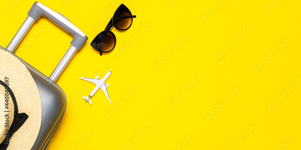 Beach background. Womens accessories traveler: suitcase, white plane, sunglasses on yellow background with empty space for text. Design of summer vacation holiday concept.