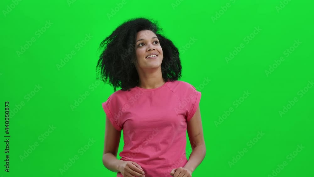 Portrait of young female African American looking around with wow delight and tenderness. Black woman with curly hair poses on green screen in the studio. Close up. Slow motion ready 59.97fps. Portrait of young female African American looking around with wow delight and tenderness. Black woman with curly hair poses on green screen in the studio. Close up. Slow motion ready 59.97fps.