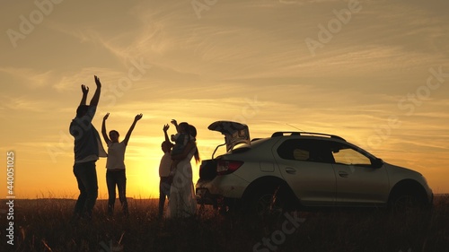 Funny family Dad with daughter on his shoulders, mom and children dance and admire beautiful sunset. Parents and children stopped for a break by car. Happy family travels by car. Car travel concept.