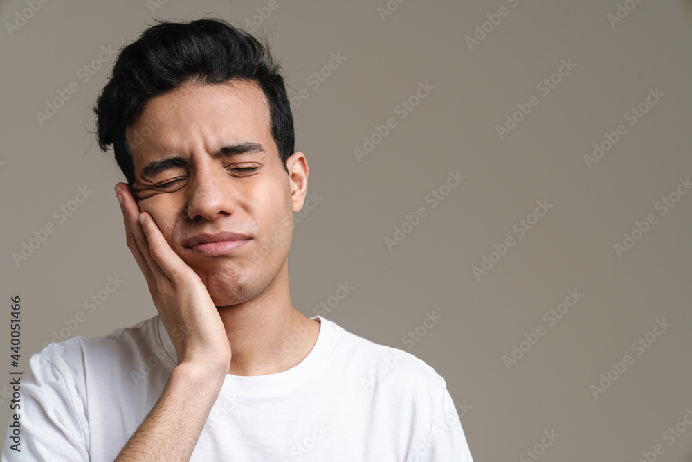 Fototapeta premium Brunette hispanic man with toothache frowning and rubbing his cheek