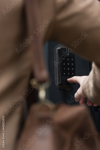 partial view of blurred man pressing button on intercom keypad.