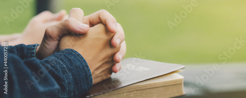 Hands folded praying over a Bible, hands over soft focus Bible.For banner.Holy Bible in church concept for faith, spirituality,worship and religion.