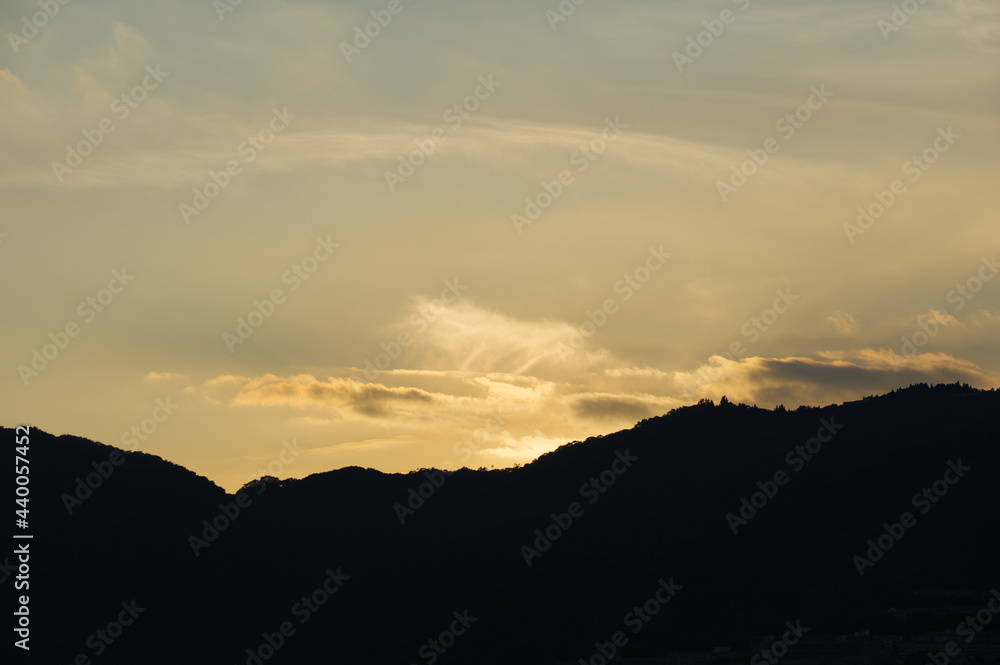 日の入り前の六甲山。西の空と雲がオレンジ色に染まるマジックアワー。1日の終わり。 日の入り前の六甲山。西の空と雲がオレンジ色に染まるマジックアワー。1日の終わり。