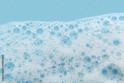 White cosmetics foam texture on blue background. Cleanser  shampoo bubbles  wash - liquid soap  shower gel  shampoo. Texture of white foam on rose background. Cosmetics banner with copy space.