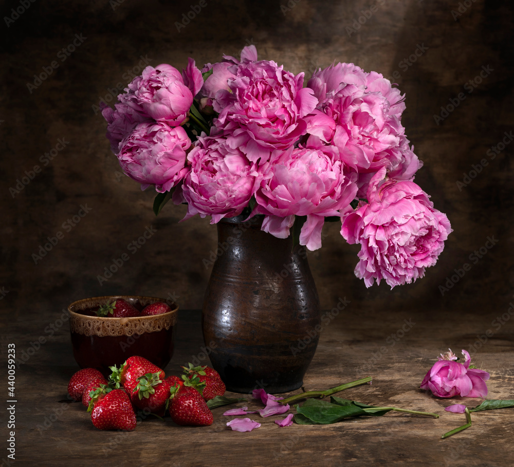 Beautiful bouquet of pink peonies in vase and strawberries in a bowl