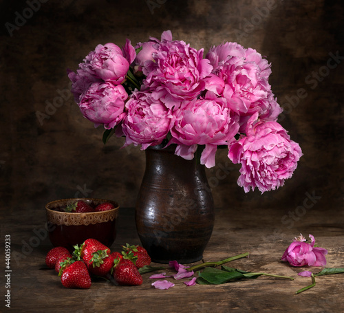 Obraz na płótnie Beautiful bouquet of pink peonies in vase and strawberries in a bowl w salonie