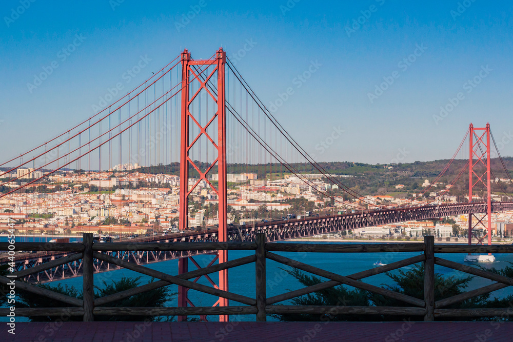 Fototapeta premium View from Almada of suspension Ponte 25 de Abril bridge (The 25th April Bridge) over river Tejo in Lisbon, Portugal. Bridge alike Golden gate in Portugal. 