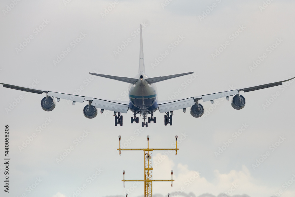 Fototapeta Big cargo aircraft is landing on the airstrip of Milan Malpensa Airport, Italy. Wings, fuselage and engine are visible. Sky with clouds in the background.