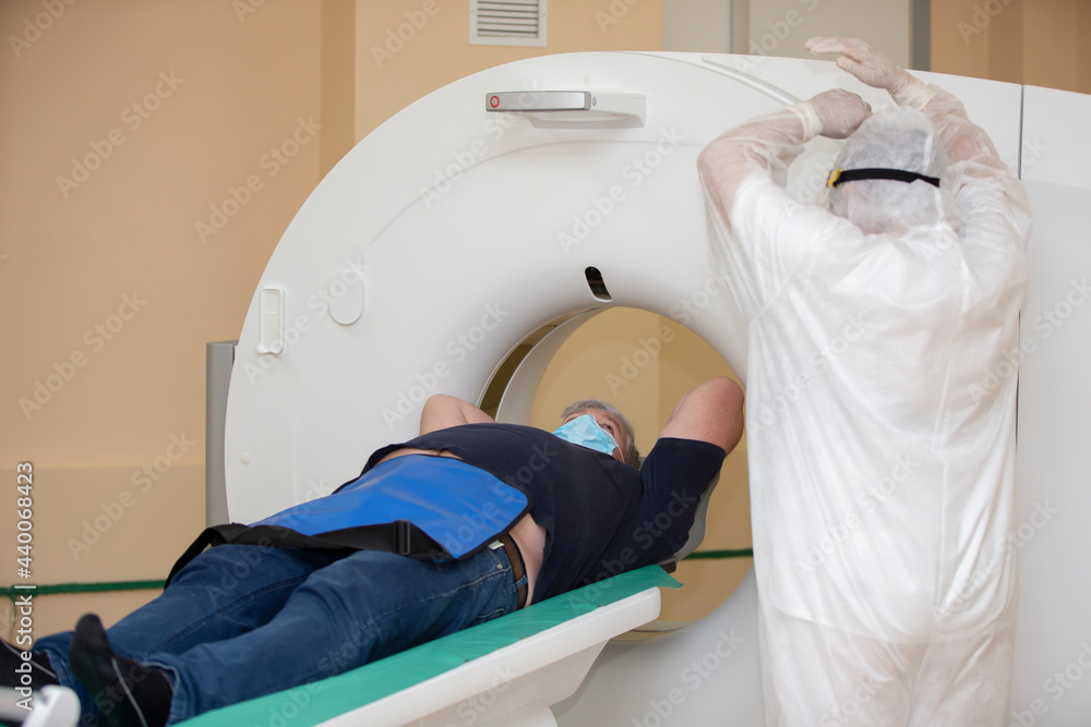 Doctors in protective medical suits are doing an MRI scan to a patient with coronavirus infection. Doctors in protective medical suits are doing an MRI scan to a patient with coronavirus infection.