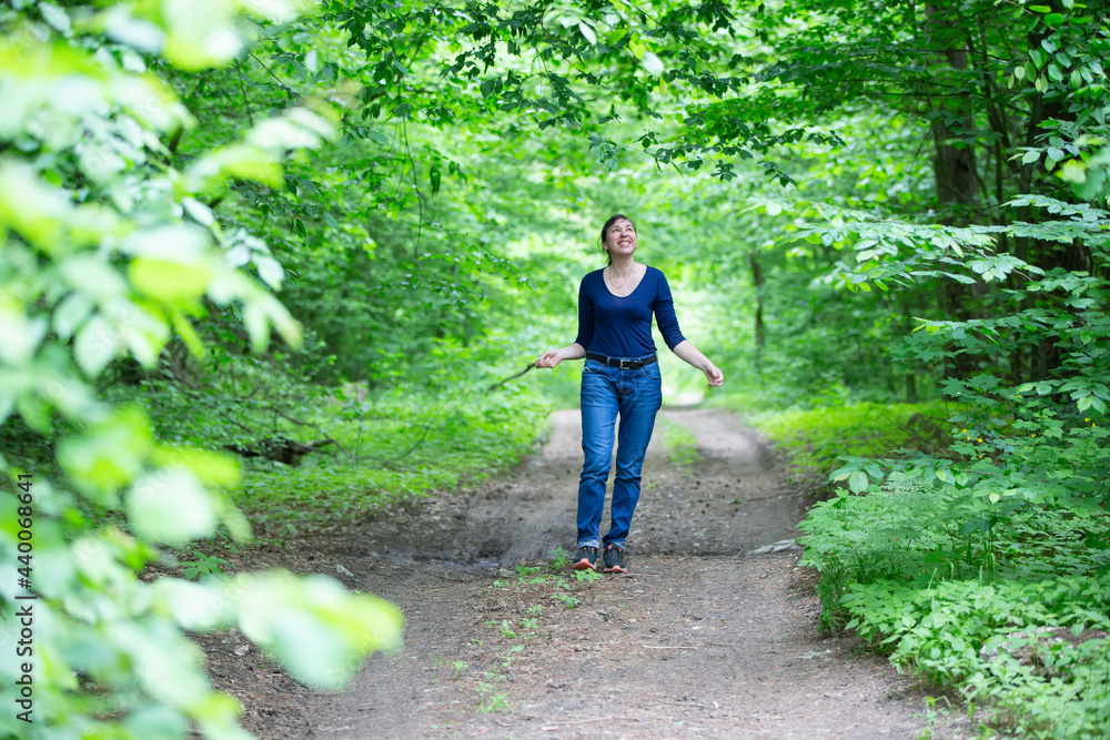 Happy middle-aged woman walks through the summer forest. Happy middle-aged woman walks through the summer forest.