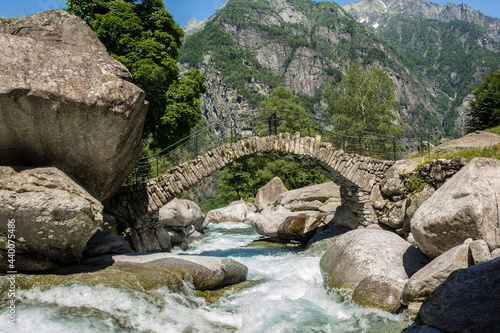 The ancient roman stone bridge at Puntid high over the Foroglio village in the Maggia valley, Tessin, Switzerland photo