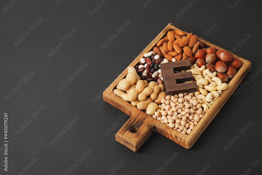 Board with different healthy nuts and beans rich in vitamin E on dark background Board with different healthy nuts and beans rich in vitamin E on dark background